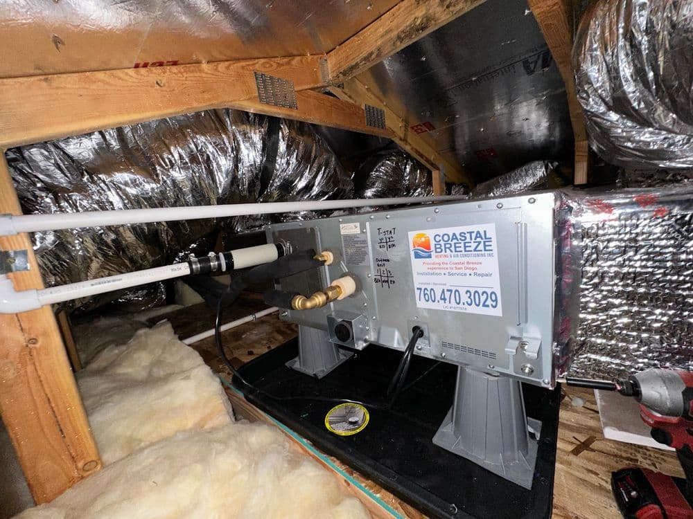 Residential HVAC system installation in attic with Coastal Breeze branding and contact info.