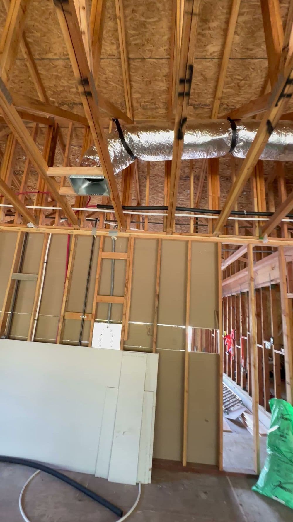 Interior view of a home under construction, showcasing wooden framing and ductwork installation.
