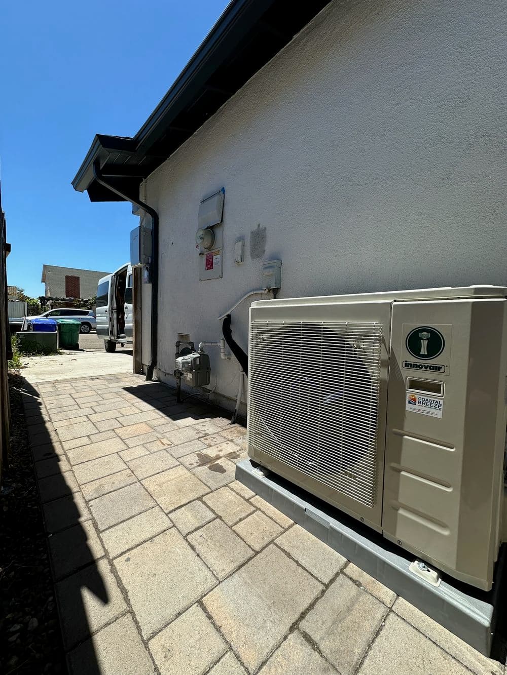 Energy-efficient air conditioning unit installed beside a home, featuring a clear blue sky.