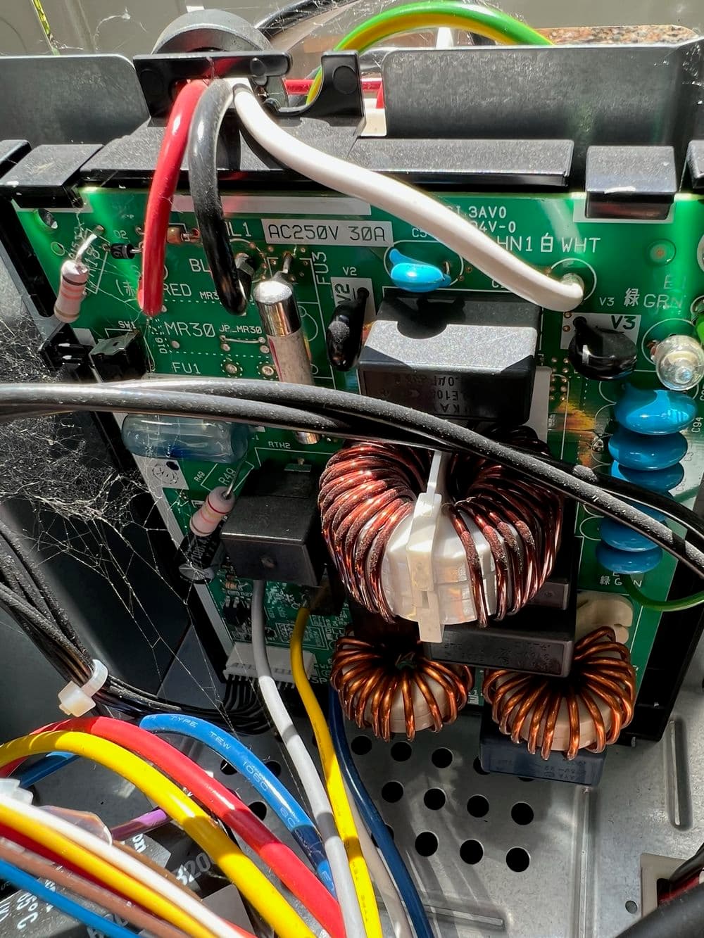 Close-up of electrical circuit board with wires and copper coils for a power supply unit.
