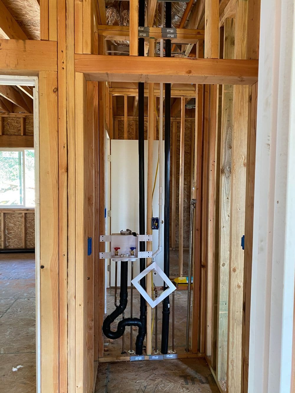 Plumbing installation in a framed interior of a new home under construction.