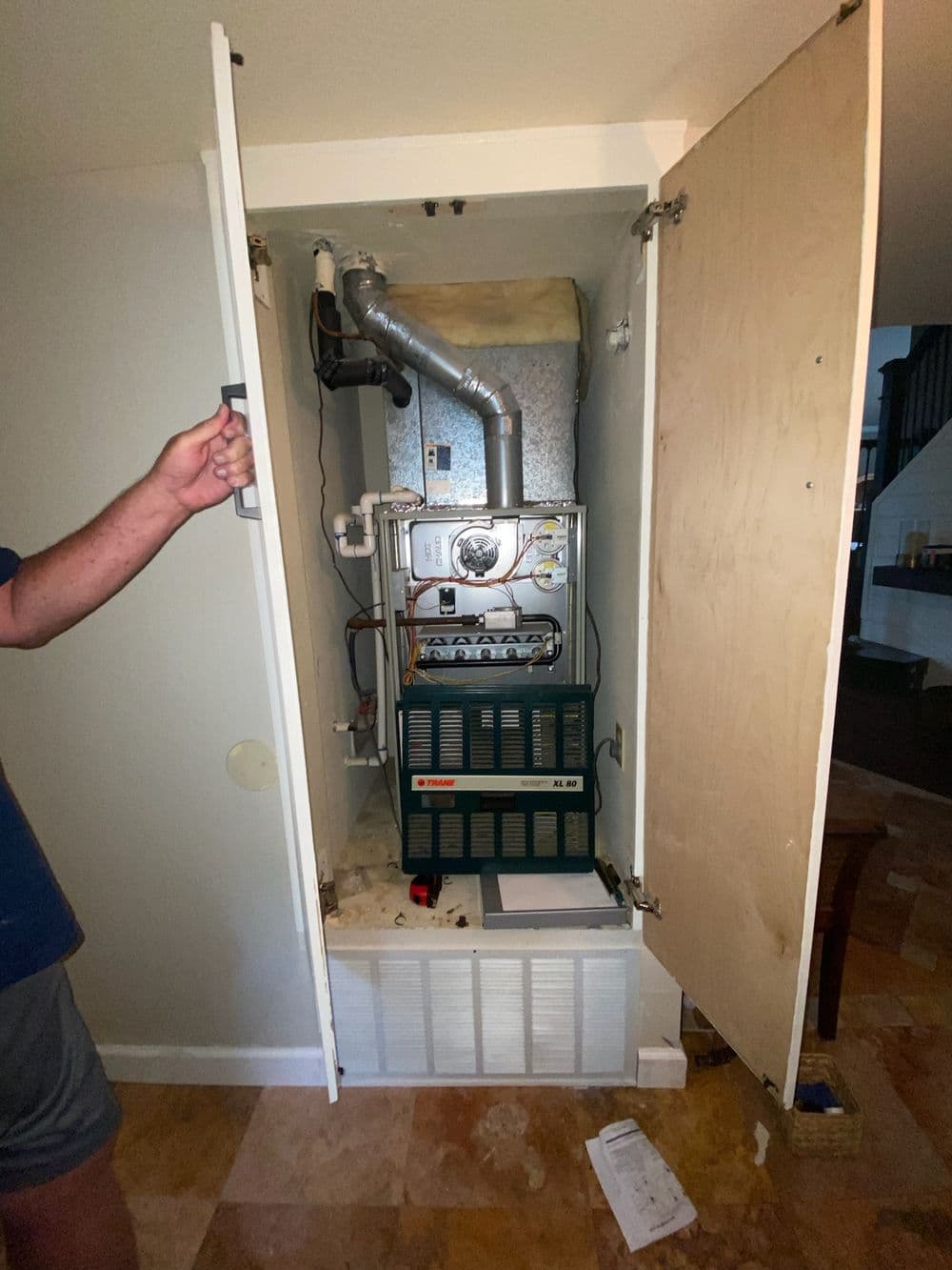 Interior view of a furnace in a closet with access panels opened for maintenance.