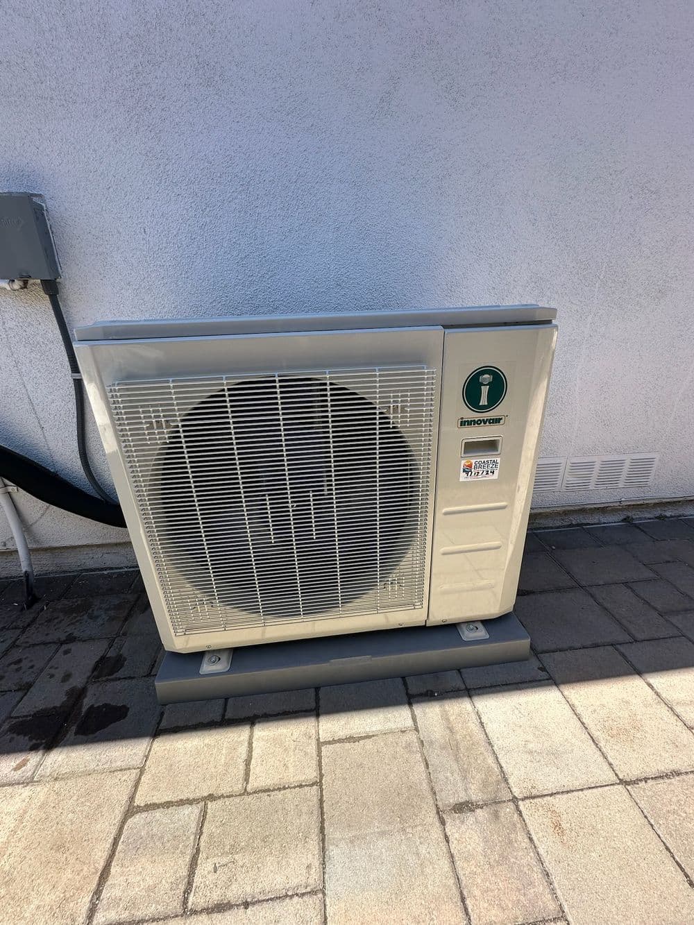 Energy-efficient outdoor HVAC unit installed on a patio with pavers.