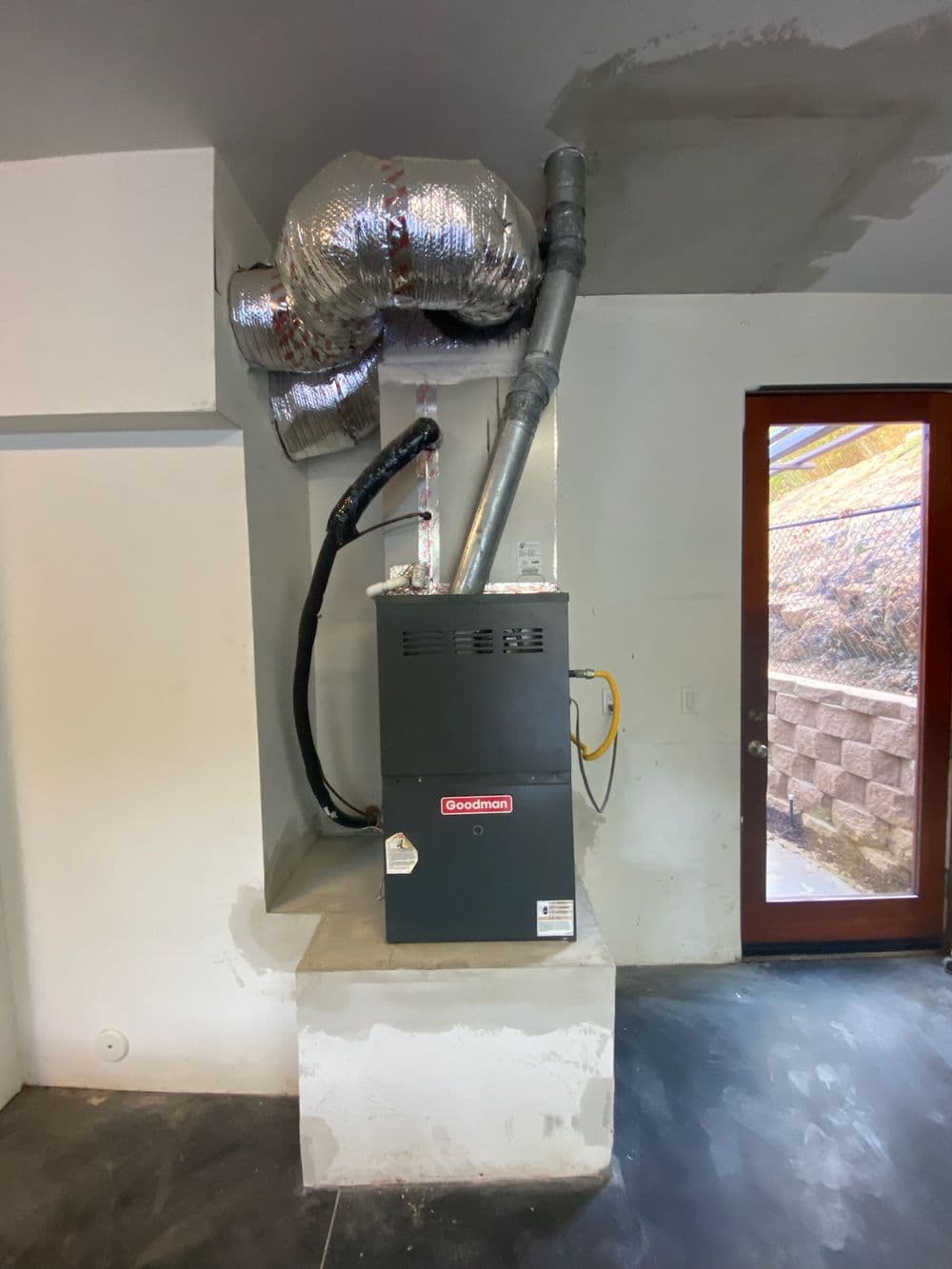 Goodman furnace installed in modern basement with ductwork and venting system.