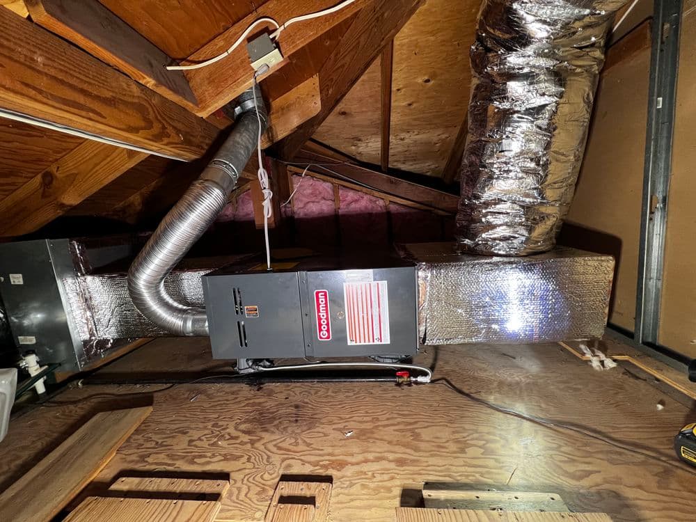 Heating system in attic with ductwork and insulation, showcasing energy-efficient design.