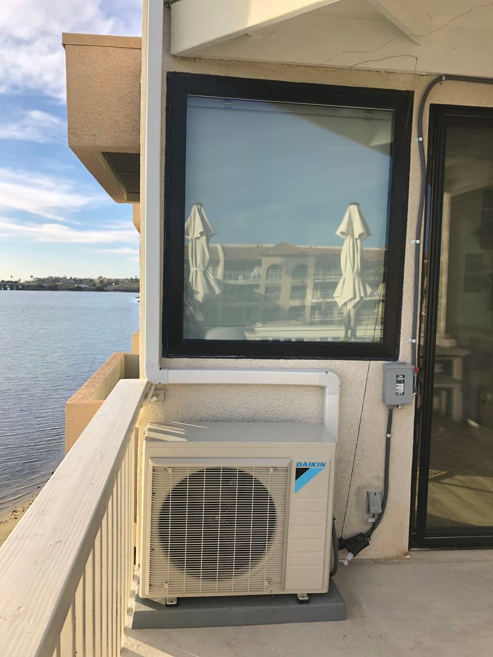 Daikin air conditioning unit installed on a balcony overlooking a body of water.