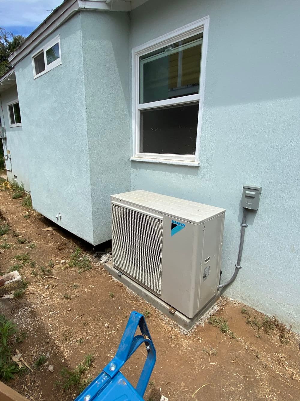 Air conditioning unit installed outside a residential building on a sunny day.
