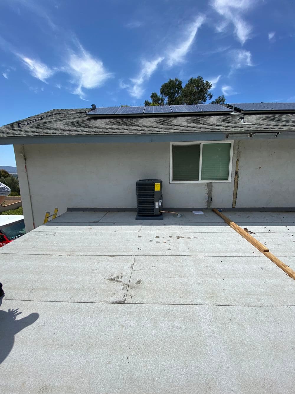 Roof with solar panels, air conditioning unit, and clear blue sky in the background.