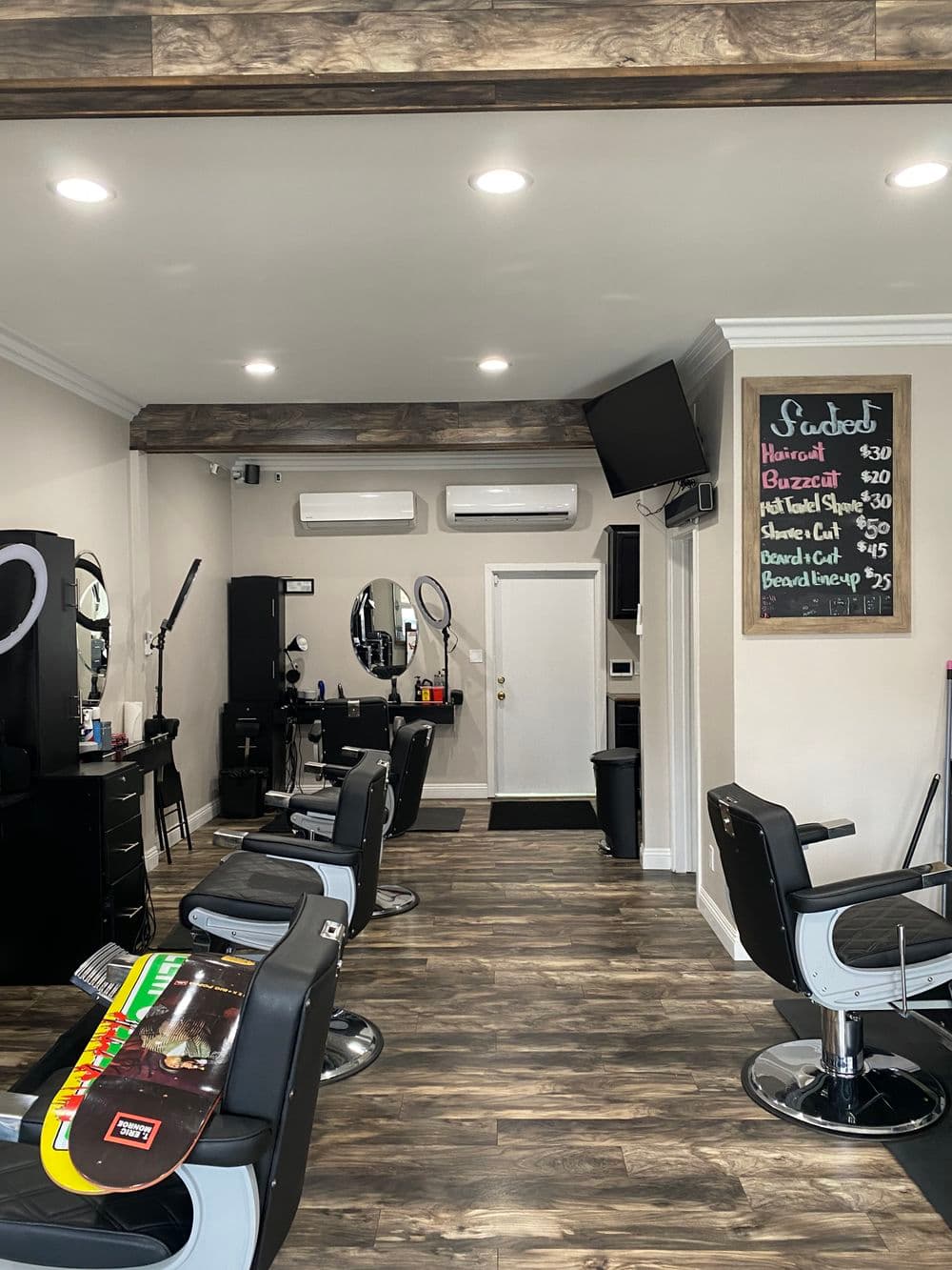 Interior of a modern barbershop featuring styling chairs, mirrors, and a service menu board.