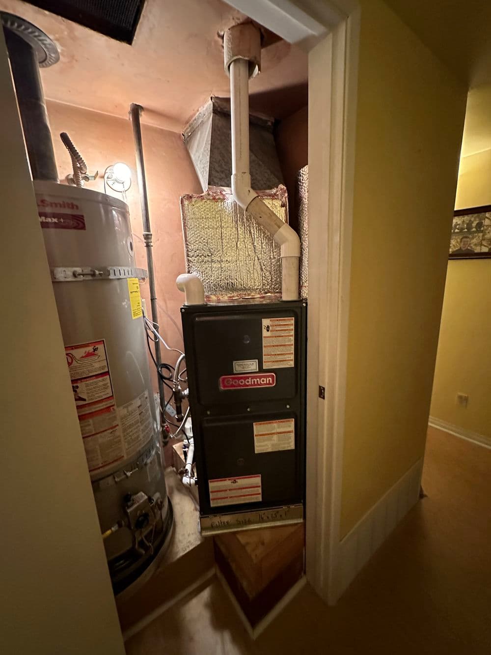 Goodman HVAC system with water heater in residential hallway. Efficient heating setup.