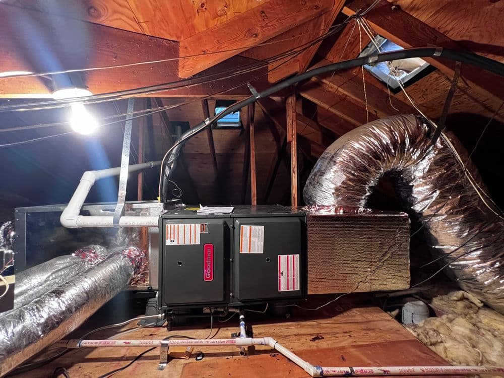 HVAC system with ductwork in an attic space, showcasing insulation and wooden beams.