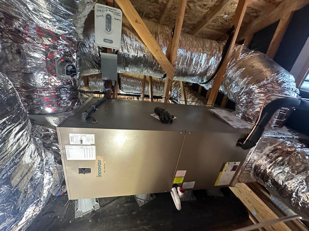 Modern HVAC unit installed in attic with insulated ductwork for efficient heating and cooling.