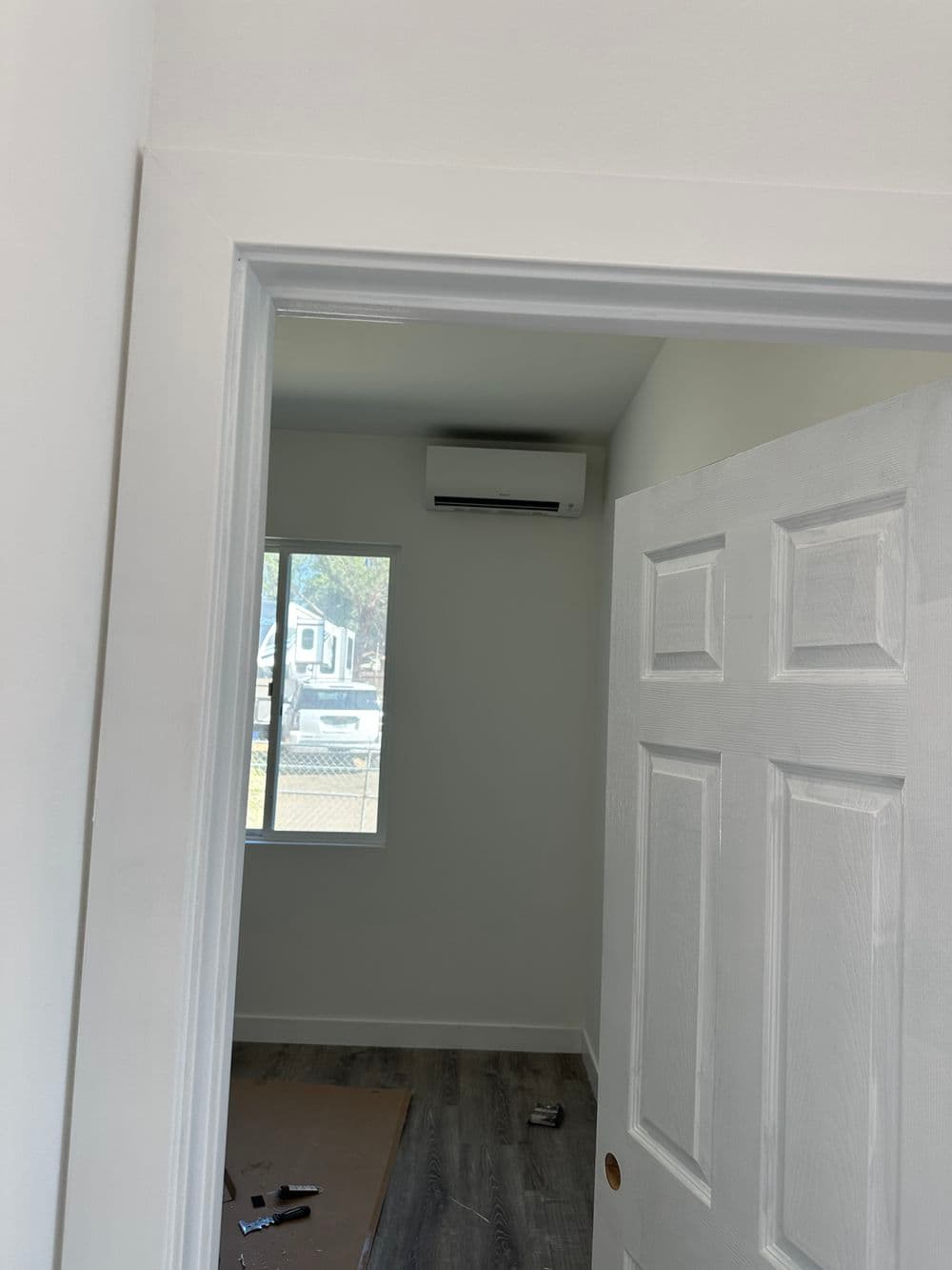 Interior view of a room with a white door, window, and air conditioner unit.