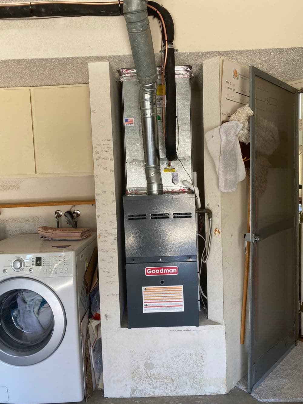 Goodman furnace installed in a laundry room with a washing machine nearby.