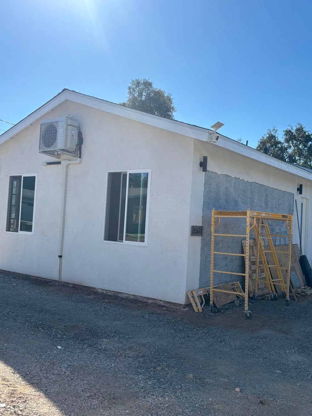 White modern house under renovation with scaffolding and air conditioning unit.